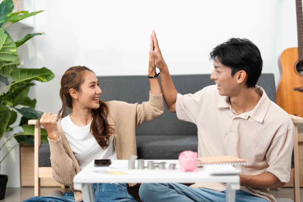 coppia che batte il cinque sul tavolino salvadanaio e risparmi